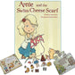 The image features the "Annie and the Swiss Cheese Scarf: Deluxe Gift Set" by Never Not Knitting, authored by Alana Dakos and illustrated by Neesha Hudson. Surrounding the gift set are related items including a children's puzzle, paper dolls, and various cut-out accessories like clothing and tools.