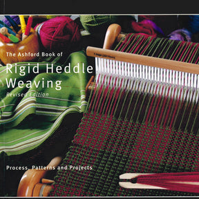 A book cover titled "Ashford Book of Rigid Heddle Weaving, Revised Edition" by Ashford Handicrafts Limited features vibrant multicolored woven fabrics. In the foreground is a weaving loom with green, red, and pink yarn. Perfect for home study use, the subtitle reads “Process, Patterns, and Projects.”