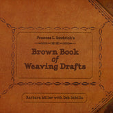 A vintage-style book cover with an intricate design featuring decorative borders and elegant central text. The title reads "Brown Book of Weaving Drafts" by Frances L. Goodrich. Smaller text below states, "Barbara Miller with Deb Schillo." This book, published by Schiffer Publishing Co., offers traditional weaving drafts presented in modern translations.