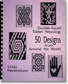 Purple book cover featuring geometric patterns and text that reads “Double-Faced Tablet Weaving: 50 Designs from Around the World” by Linda Hendrickson. The cover showcases five black-and-white ethnic motifs arranged around the text. The book is spiral-bound for easy use.