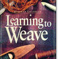 The cover of the book "Learning to Weave" by Deborah Chandler from Ingram Content showcases a woven textile in vibrant shades of red and purple. The surrounding elements include essential weaving tools such as a shuttle with thread. This comprehensive guide also explores advanced techniques and weave structures for those aiming to perfect their weaving skills.