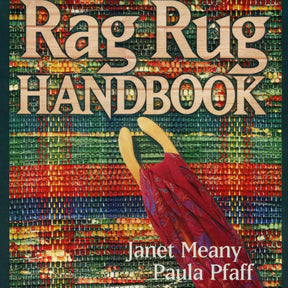 The cover of the "Rag Rug Handbook - 2nd Edition" by Janet Meany and Paula Pfaff from Great Northern Weaving showcases a vibrant woven rug background adorned with traditional patterns. At the center, wooden weaving tools and fabric strands vividly illustrate the art of weaving rag rugs. The title is prominently displayed at the top, while the authors' names are positioned at the bottom.