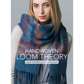 A person with long blonde hair wears a thick, blue-toned multicolored scarf adorned with fringe details. They are dressed in a light-colored top. Text on the image reads: "Handwoven Loom Theory Vol III - Rigid-heddle scarf collection - eBook printed copy by Long Thread Media.