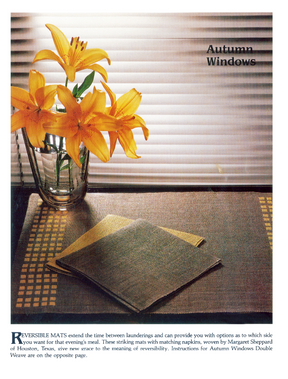 A vibrant vase of orange lilies sits on a wooden table beside folded Handwoven Design Collection #11 heirloom table linens, with sunlight filtering through the closed blinds to cast soft shadows. In the upper right corner, you see "Autumn Windows" in text. The linens are part of Long Thread Media's exquisite collection.