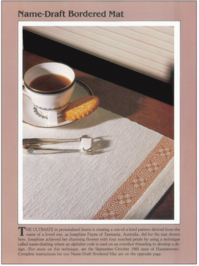 A cup of tea with a biscuit on a saucer, artfully displayed on fabric adorned with a decorative border and accompanied by a fork. This exquisite fabric showcases personalized embroidery from the Handwoven Design Collection #11, an heirloom offering by Long Thread Media. Text beneath delves into the craft techniques featured in their eBook for creating personalized table linens.