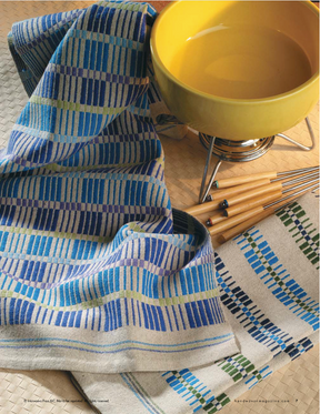 A vibrant yellow fondue pot on a stand is complemented by forks with wooden handles. The scene is enhanced with blue, green, and beige checkered cloths elegantly positioned next to it, all resting on a meticulously woven surface from the Handwoven Design Collection #18 by Long Thread Media.