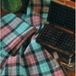 A handwoven design from Long Thread Media's "Collection #18, A Treasury of Towels" eBook is elegantly displayed beside an open vintage waffle iron. In the background, a green jug adds a splash of color, while a silver fork lies partially visible next to the iron on a wooden surface.