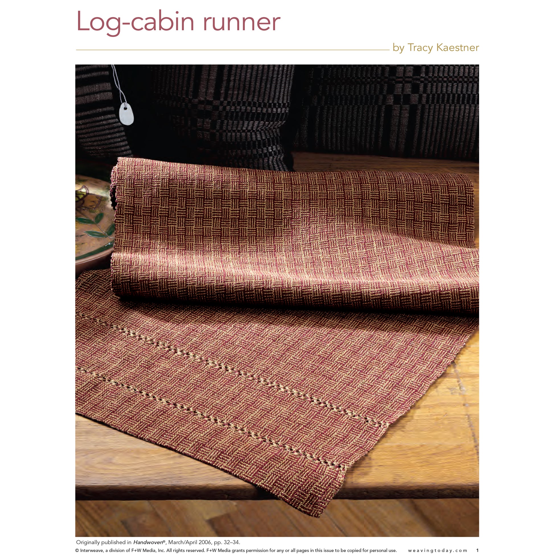 A piece from the Handwoven Special Pattern Collection – 5 Gifts To Weave: eBook Printed Copy by Long Thread Media is partially rolled out on a wooden surface. This woven fabric runner showcases an intricate log-cabin geometric design in shades of red and beige, with a tag attached to one side.