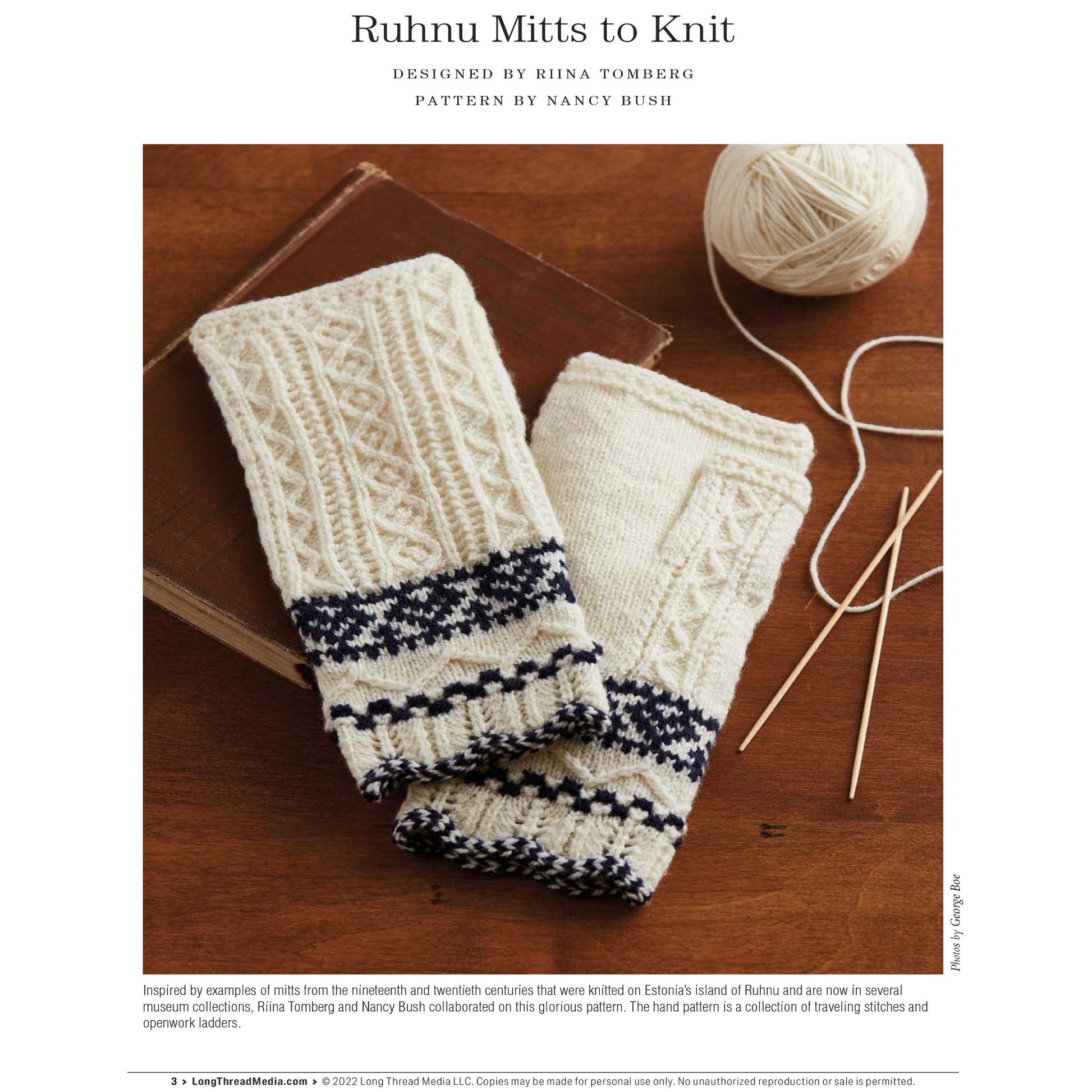 The image depicts a pair of cream-colored knitted mitts with intricate blue patterns, designed by Riina Tomberg and featuring a pattern by Nancy Bush. These mitts are showcased alongside knitting needles and a ball of cream-colored yarn on a brown surface. They can be found in the "PieceWork Presents: Fingerless Mitts for All Seasons – eBook printed copy" by Long Thread Media.