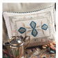 An Elegant Embroidery with 5 Beautiful Projects to Stitch eBook from Long Thread Media is displayed against a patterned fabric background. In front of the book sits a silver teapot, and multicolored embroidery threads are scattered nearby.