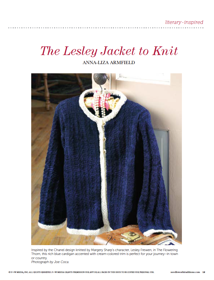 A navy-blue knitted jacket with cream-colored trim hangs on a decorative hanger, paired with the text "PieceWork Presents: Literary-Inspired Projects to Knit, Crochet, Hook, and Cross-Stitch" by Long Thread Media. The Lesley Jacket is displayed on a stand in a cozy interior setting.