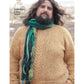 A person with a beard wearing a beige cable-knit sweater and a multicolored, green-hued scarf stands outdoors. The image is featured in the "Magical Knitted Costume Collection – eBook printed copy" by Long Thread Media. In the background, there are faint snowy plains visible.