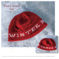 A red knitted hat with the words "WINTER GAMES" stitched in white around the brim is displayed on a snowy surface, accompanied by the text "Winter Games Hat - Laurie Sundstrom" written above in red. An additional smaller image of the hat appears at the bottom. This design is featured in Long Thread Media's product, "Winter Games: 4 Projects to Knit & More – eBook printed copy.