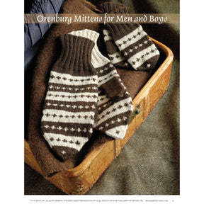 A copy of "Knitting the North: 4 Traditional Mitten Patterns from Northern Europe – eBook printed copy" by Long Thread Media is displayed on an antique wooden suitcase, alongside a pair of brown and cream patterned mittens featuring Nordic-style designs. The text above reads "Orenburg Mittens for Men and Boys.