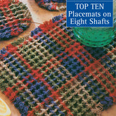 On a wooden table adorned with glassware and citrus fruit slices, an array of brightly colored woven placemats featuring textured patterns is showcased. The cover text highlights "Best of Handwoven, Top Ten Placemats on Eight Shafts," an eBook by Long Thread Media that presents a vibrant collection of multi-shaft pattern weaves.