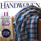 Cover of Handwoven Magazine Jan/Feb 2023 issue by Long Thread Media. A plaid wool blanket in blue, green, and purple hues is draped over a beige couch. The cover text highlights articles on dyeable wool projects, scarves and shawls, a stash-saving guide, and sustainable yarns.