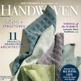 Handwoven Magazine March/April 2023 issue by Long Thread Media. The cover features folded woven textiles in various shades of green and purple in the foreground. The headline reads, “11 weaving life projects drawn from architecture,” with additional subtitles on weaving techniques and care tips.