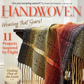 The cover of Long Thread Media's "Handwoven Magazine Spring 2024" edition features a vibrant woven fabric with intricate patterns and fringed edges elegantly draped over a chair. The magazine highlights articles on warping techniques, weaving projects, and textile tourism.