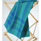 The printed version of Long Thread Media's Best of Handwoven Technique Series: Twills on Four Shafts eBook is elegantly draped over a wooden drying rack, displaying its intricate blue and green plaid patterns.