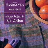 The cover of the "Best of Handwoven Yarn Series: A Dozen Projects in 8/2 Cotton" eBook by Long Thread Media showcases a woven fabric featuring a purple and green plaid design, skillfully crafted by weavers. Beside it rests an orange fruit bowl, while the text emphasizes "A Dozen Projects in 8/2 Unmercerized Cotton.