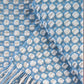 A close-up of the Handwoven's Master Weaver Collection fabric with a grid design. The fabric features soft, rounded white squares inside light blue squares. One edge of the fabric has light blue fringe, hinting that it could be a blanket or scarf from Long Thread Media's collection inspired by Madelyn van der Hoogt's projects and lessons. The texture appears soft and woven.