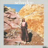 A person in a flowing pink and brown dress stands on rocky terrain with large, colorful rock formations in the background. The cover text reads "Selvedge" at the top and "The Fabric of Your Life" at the bottom, evoking craftsmanship far removed from fast fashion trends. This is Selvedge - Issue 114: Regeneration by Selvedge.