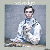 A person dressed in a vintage-inspired outfit poses on the cover of Selvedge magazine's Issue 115: Pioneers. They hold a large pair of scissors with a measuring tape draped over their hands, embodying the emerging makers in the textile world. The background is neutral, and the cover headline reads "The Fabric of Your Life.