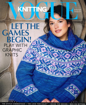 A woman in a blue and purple knit sweater featuring geometric patterns is seated, facing forward. The magazine cover displays the text: "Soho Publishing - Vogue Knitting Winter 2022/23: Let the games begin! Play with graphic knits." Dive into Stitch Cinematique this season!