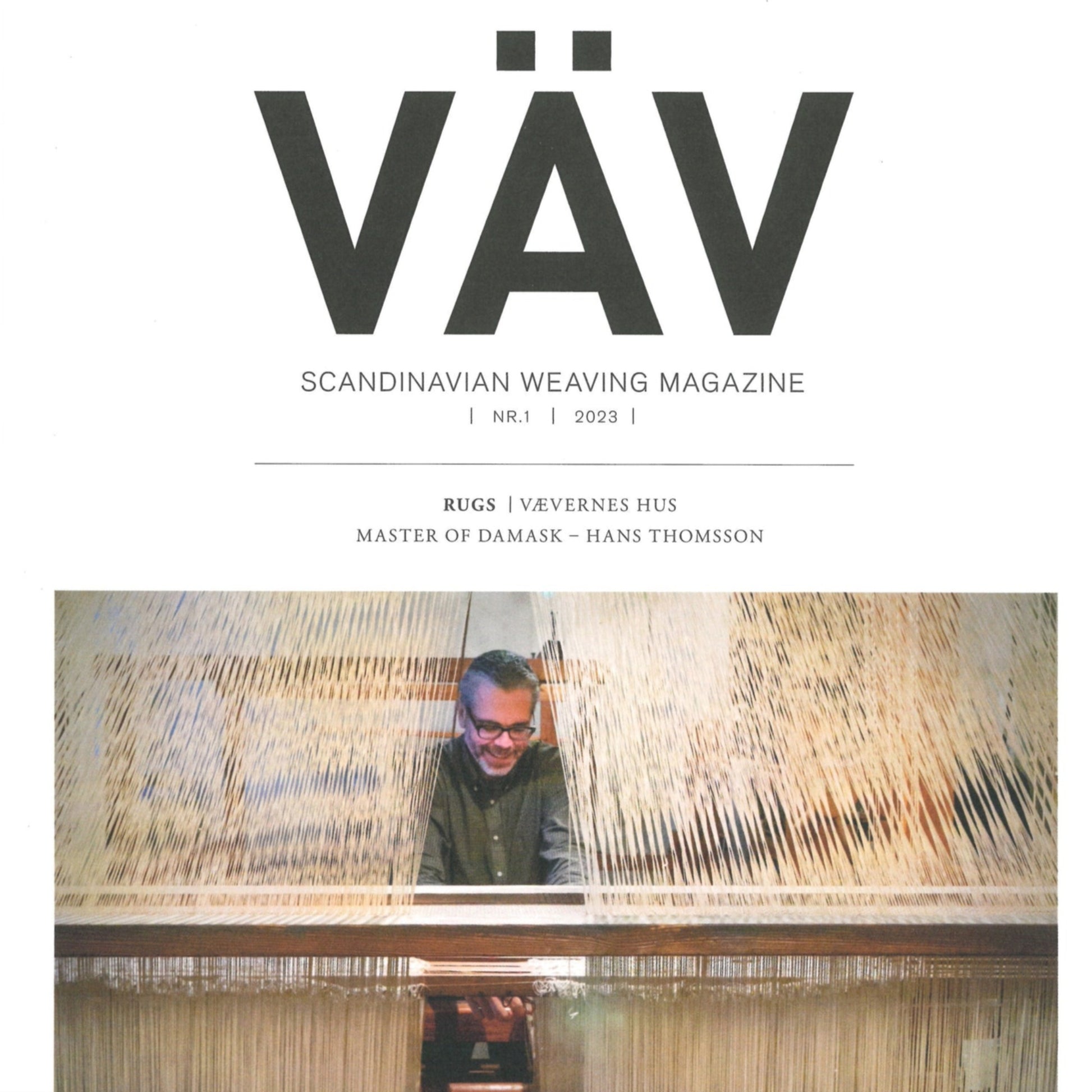 Cover of VÄV Magasinet 1/23 from VÄV Magazine. Below the title, it reads "Rugs," "Vävernes hus," and "Master of Damask - Hans Thomsson." The cover image features a smiling individual weaving on a loom, showcasing the artistry of Viking-Age Furnishing Textiles.