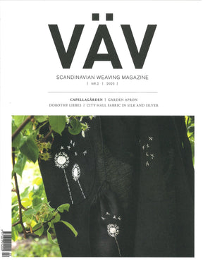 Cover of VÄV Magasinet 2/23 by VÄV Magazine. The cover features a black handwoven fabric with white dandelion embroidery, set against a background of green foliage. The bottom text mentions articles on Capellagården, garden apron, Dorothy Liebes, and City Hall fabric.