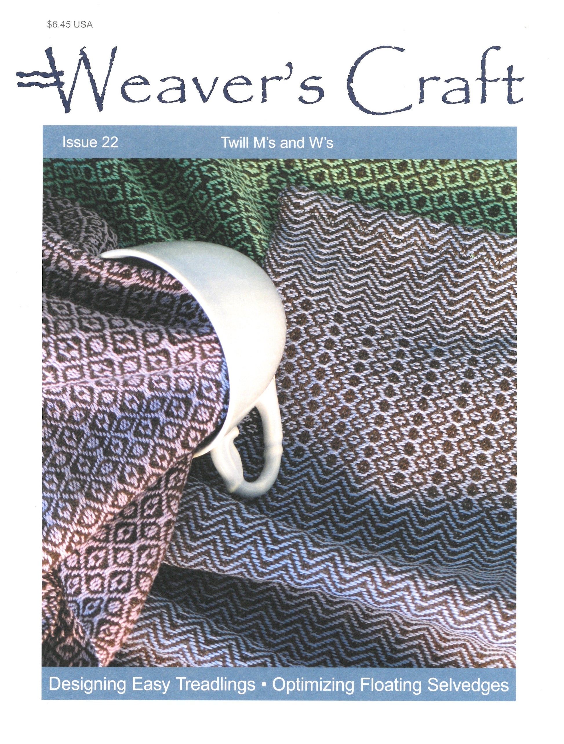 Cover of Plain Tabby Press's magazine, Weaver's Craft Issue 22: Twill M's and W's, featuring a white cup resting on folded, intricately woven fabric in shades of green, pink, and gray with a zigzag and diamond pattern. Headlines include "Designing Easy Treadlings," "Optimizing Floating Selvedges," and "Exploring M's and W's Twills in Weaving.