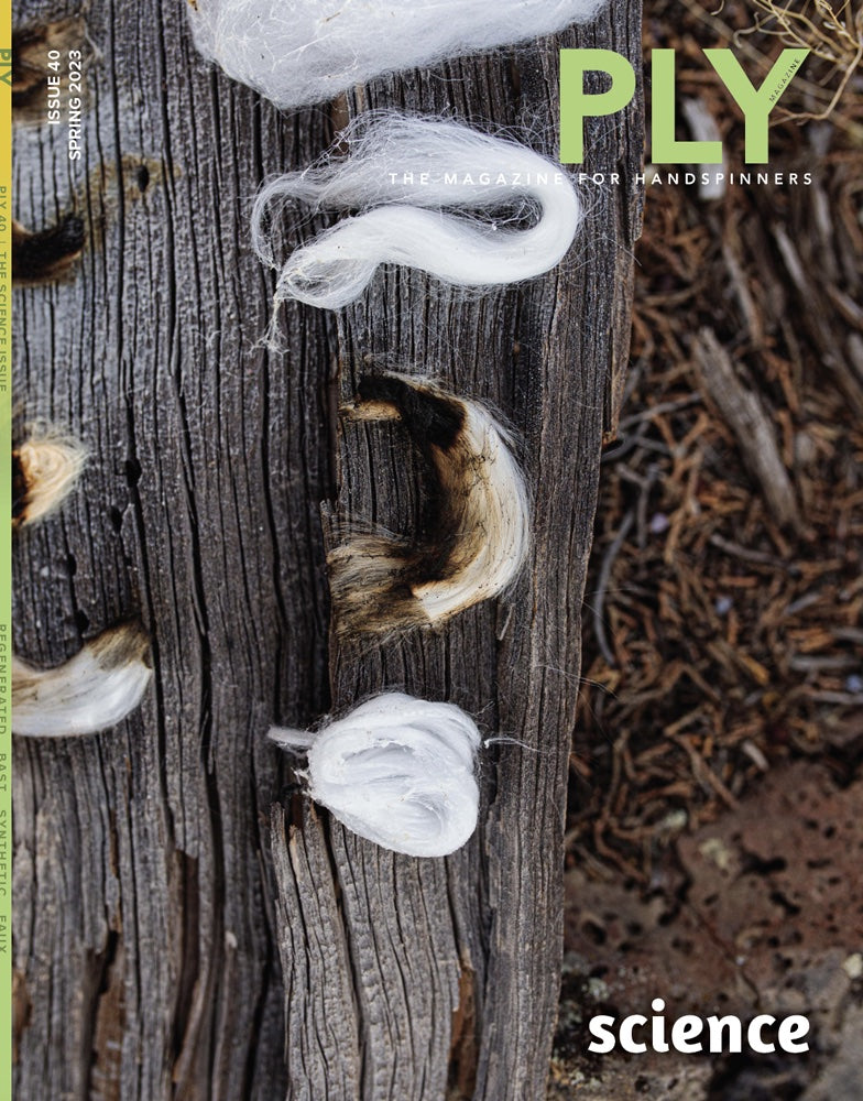 Bundles of white and brown fibers are laid on a textured wooden surface, framed by a backdrop of dried grass and dirt. The cover of PLY Magazine’s Issue 40 for Spring 2023, titled "The Science Issue," features insights into fiber preparation and bioengineered fibers.