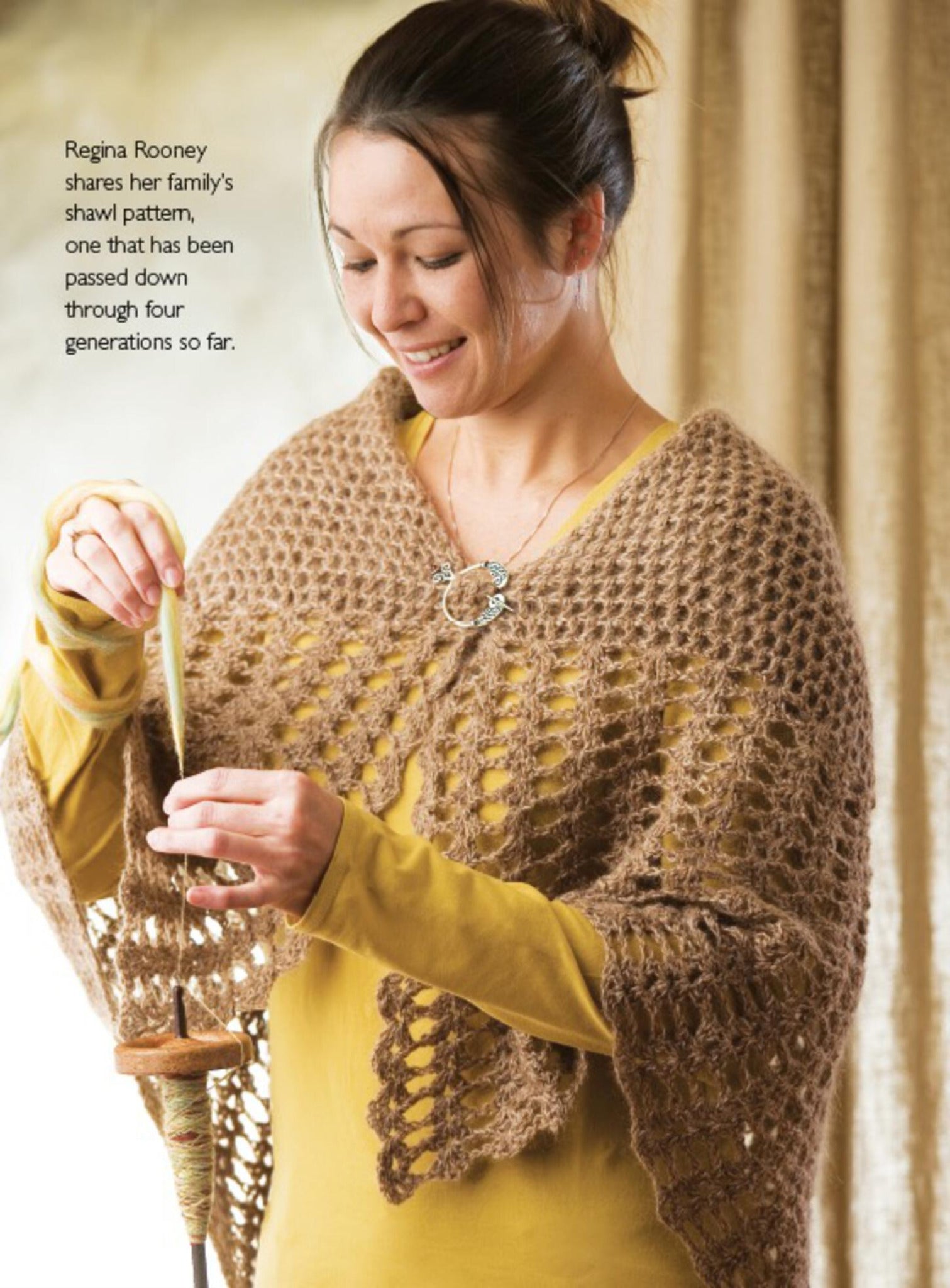 A woman wearing a handmade shawl from Long Thread Media's "Spin-Off Presents: 7 Handspun Shawls to Knit, Crochet, and Weave - eBook Printed Copy" works with a drop spindle and wool. Text in the image reads, "Regina Rooney shares her family's shawl pattern, one that has been passed down through four generations so far." The shawl features an intricate, lace-like pattern.