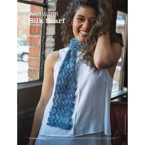 A woman with curly hair smiles while wearing a white sleeveless button-up top and a knitted scarf. She appears to be inside a rustic building with brick walls and large windows. Text on the image reads, "Long Thread Media's Spin Off Presents: Lovely Lace: 6 Projects to Spin and Knit - eBook Printed Copy.