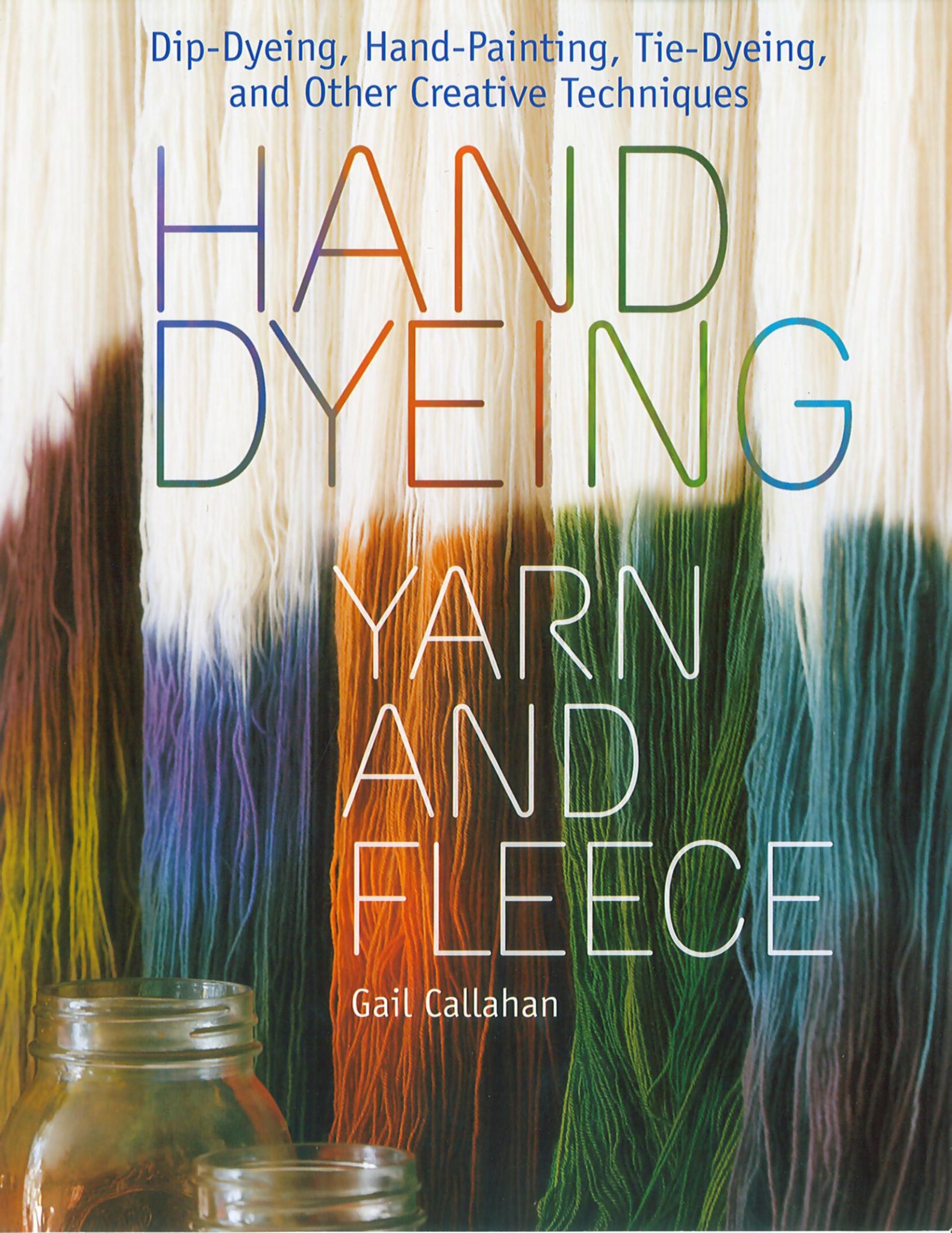 The cover of "Hand Dyeing Yarn and Fleece," published by Workman Publishing - Storey and authored by Gail Callahan, features the title in large, colorful letters against a backdrop of variously dyed yarn strands in shades of white, purple, blue, green, and orange. Showcasing creative dyeing methods, it also includes a glass jar at the bottom.