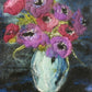 The "Art in Felt & Stitch" by Ingram Content showcases a vibrant mixed-media artwork featuring a bouquet of intricately detailed purple and pink flowers crafted through needle felting. The flowers, with their green stems, are arranged in a textured, light blue vase set against a deep blue and black background. This piece exemplifies the artist's skillful use of color and texture.