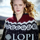 A person with long, wavy blond hair is wearing a colorful knitted sweater featuring patterns in red, white, and black. The person is outdoors, with a blurred landscape in the background. At the bottom of the image, the text "Lopi Book 38" along with Berroco's yarn ball symbol are visible.