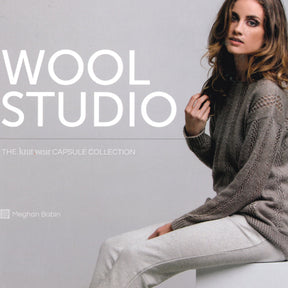 A woman sits on a white surface, wearing a gray cable-knit sweater and light-colored pants. The text “Wool Studio: The knit.wear Capsule Collection” by Ingram Content is displayed, highlighting the luxurious knitwear designs with "Meghan Babin" mentioned in smaller text at the bottom.