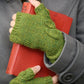 A person dressed in stylish attire, including a gray coat and green fingerless gloves from Never Not Knitting's Botanical Knits collection, is holding a red book. The title of the book, "The Post," is partially visible. The focus remains on the hands, book, and the texture of the clothing.