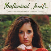 The cover of Never Not Knitting's "Botanical Knits" features a woman with long, wavy brown hair and a serious expression, adorned in an elegant orange knit sweater. Lush plant life in the background perfectly complements the book’s botanical theme inspired by trees and foliage.