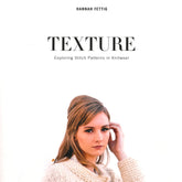 Book cover for "Texture - Exploring Stitch Patterns in Knitwear" by Never Not Knitting. The cover features a woman wearing a cream-colored knit sweater, with blonde hair styled in soft waves. She is gazing downward with a calm expression, set against a plain white background, perfectly showcasing the beauty of knitting.