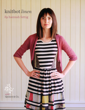 A woman with straight dark hair stands against a light-colored, vertical wooden wall. She wears a pink knit cardigan over a sleeveless black-and-white striped dress with colorful abstract patterns near the hem. Text on the image reads, "Knitbot Linen by Never Not Knitting, featuring Halcyon Yarn Block Island Blend.