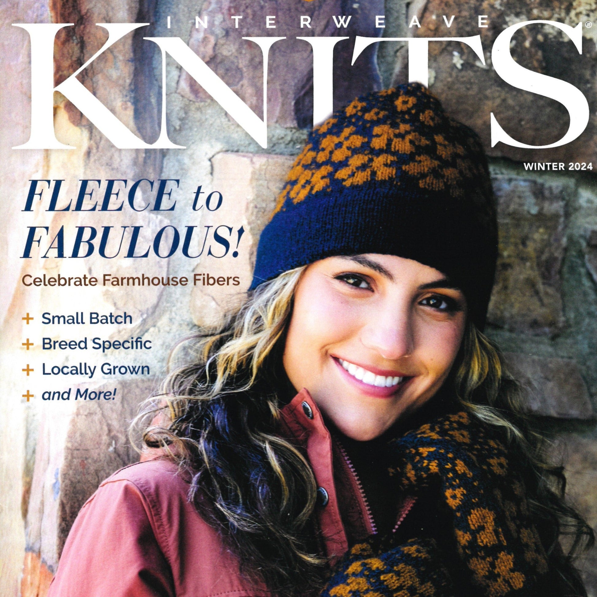 A woman wearing a knitted hat with matching scarf and a coat is smiling on the cover of Golden Peak Media's Interweave Knits Winter 2024 issue. The text highlights "Fleece to Fabulous!" and focuses on Farmhouse Fibers, featuring small batch, breed-specific wool, including luxurious Icelandic Sheep fibers.