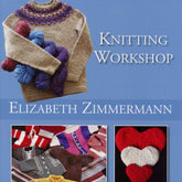 The cover of the "Knitting Workshop Updated Edition" by Elizabeth Zimmermann, published by Schoolhouse Press, features a knitted sweater, three skeins of yarn in purple, red, and blue, several knitted garments showcasing various knitting techniques, and a heart made of three sections in white, red, and beige.