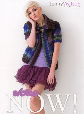 A model with short, blonde hair poses against a light background. She wears a multi-colored knitted sweater, a purple top, a layered purple skirt, and a necklace. The text on the image reads "Jenny Watson Designs" and "Noro Now!" in stylized fonts—highlighting colorful knitting patterns for designer garments by Knitting Fever / Euro Yarns.