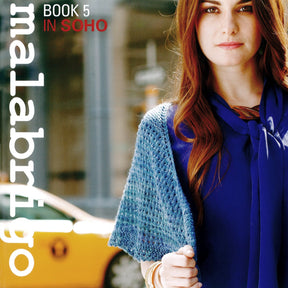 A woman with long auburn hair, wearing a blue top and an elegant knitted shawl, stands in an urban setting with a yellow taxi in the background. The text on the image reads "Malabrigo Yarn" on the left side and "Malabrigo Book 5 - In Soho" at the top.