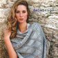 A woman with wavy, light brown hair is standing against a stone wall, modeling a light gray, intricately knitted shawl made from luxurious Merino yarns. The text "Malabrigo Book 4" by Malabrigo Yarn is displayed in the upper right corner of the image.