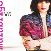 A woman with short, dark hair and purple lipstick poses with her arms crossed, wearing a colorful striped knitted shawl made from merino yarn over a beige top. The text on the left side reads "Malabrigo Book 10 - Rios" in purple and black font, representing Malabrigo Yarn.