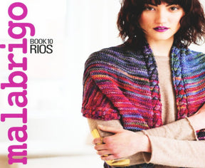 A woman with short, dark hair and purple lipstick poses with her arms crossed, wearing a colorful striped knitted shawl made from merino yarn over a beige top. The text on the left side reads "Malabrigo Book 10 - Rios" in purple and black font, representing Malabrigo Yarn.