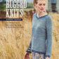 The cover of the book "Rugged Knits - 24 Practical Projects for Everyday Living" by Andrea Rangel, published by Ingram Content, showcases a woman standing in a field wearing a blue knitted sweater. The text on the cover reads "Rugged Knits" and "24 Practical Projects for Everyday Living." The background features tall grasses and blurred structures, emphasizing unique knit patterns.